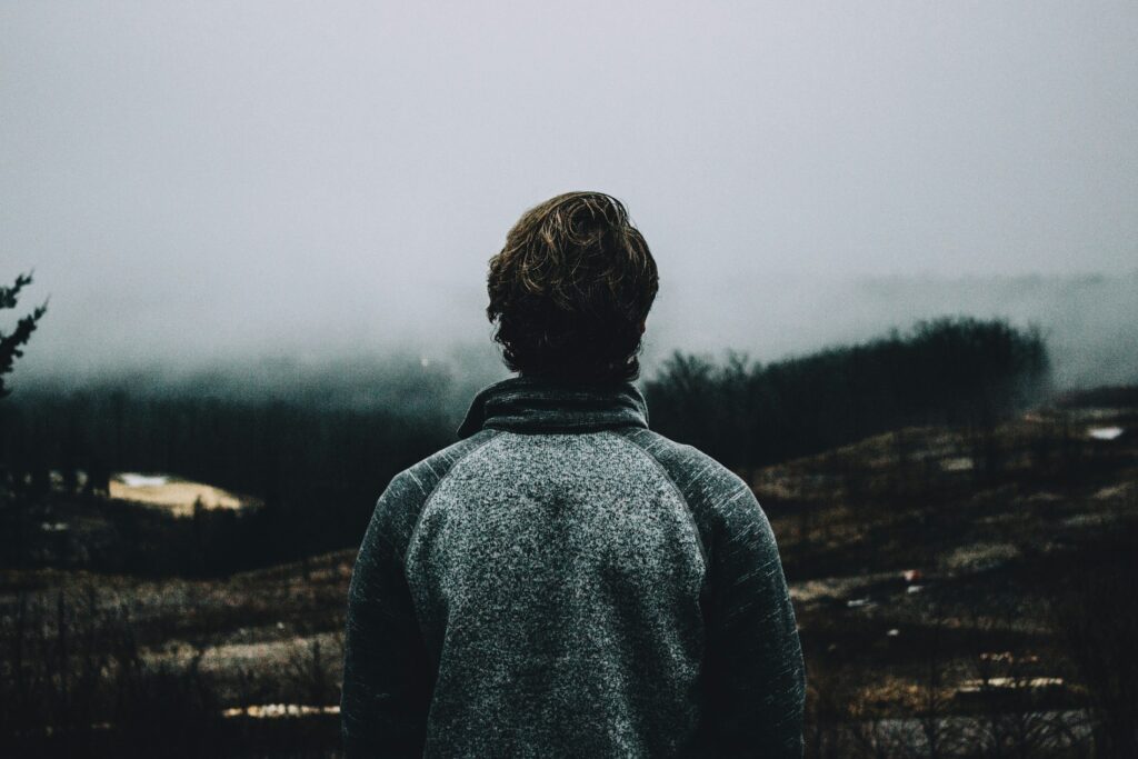 Persona de espaldas ante un paisaje cubierto de niebla